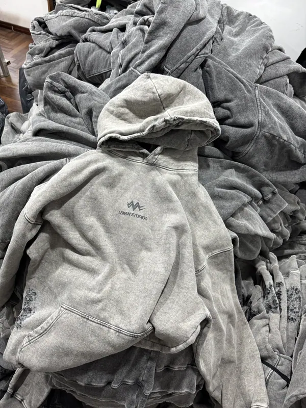 Buzo con capucha lavado gris claro sobre una pila de producción