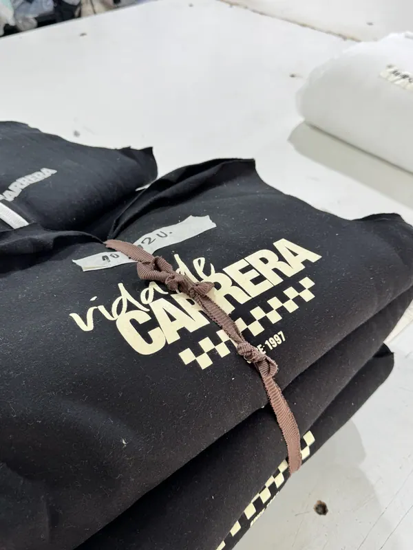 Buzos negros con estampa crema, apilados y atados por talle
