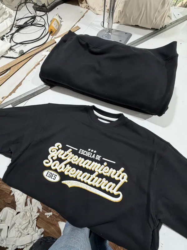 Buzos negros con estampa dorada en el frente, merch para escuela de iglesia