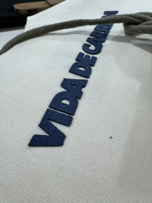 Detalle de bordado azul sobre un buzo crema
