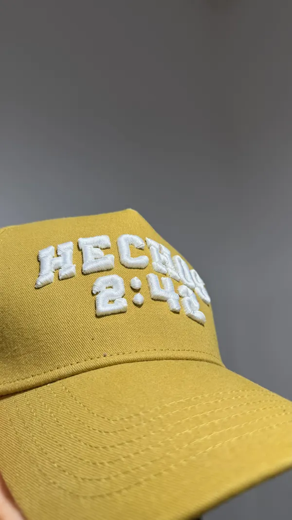 Detalle de gorra mostaza con bordado blanco en relieve