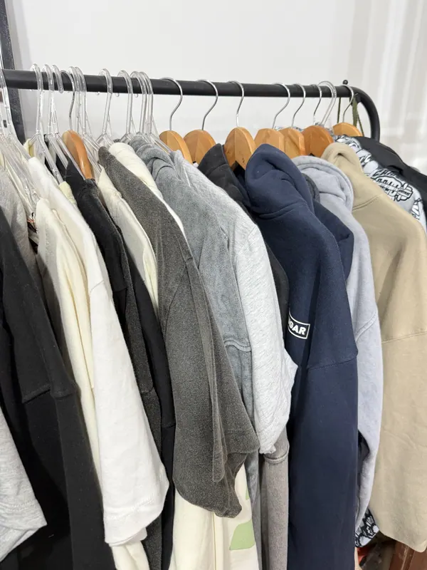 Perchero con buzos y remeras de muestra en el taller