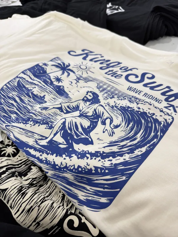 Remera crema con estampa azul de una ola en la espalda