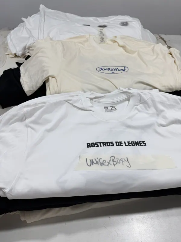 Remeras blancas y crema estampadas, dobladas para entregar
