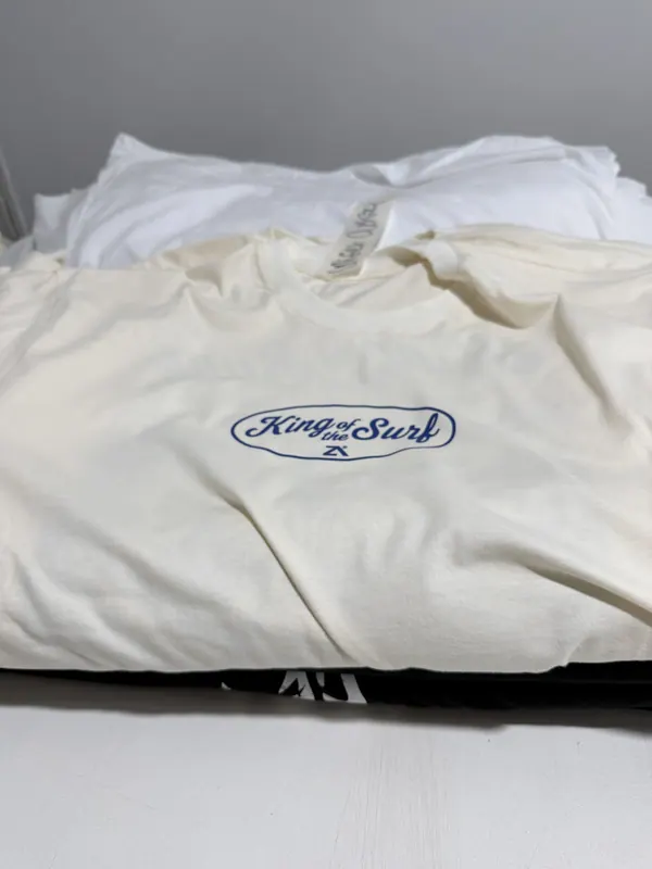 Remeras crema con logo chico en el pecho, dobladas