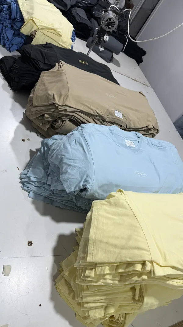 Remeras de colores dobladas y apiladas en la mesa del taller