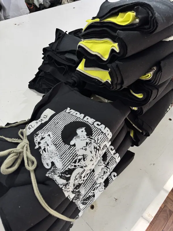 Remeras negras con estampa blanca de una moto, atadas para entregar