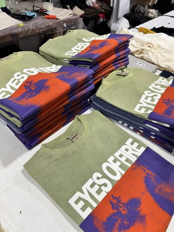 Remeras verdes con estampa a color, apiladas para entregar