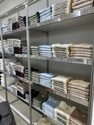 Estanterías con remeras dobladas por talle en el taller de Alta Rotura